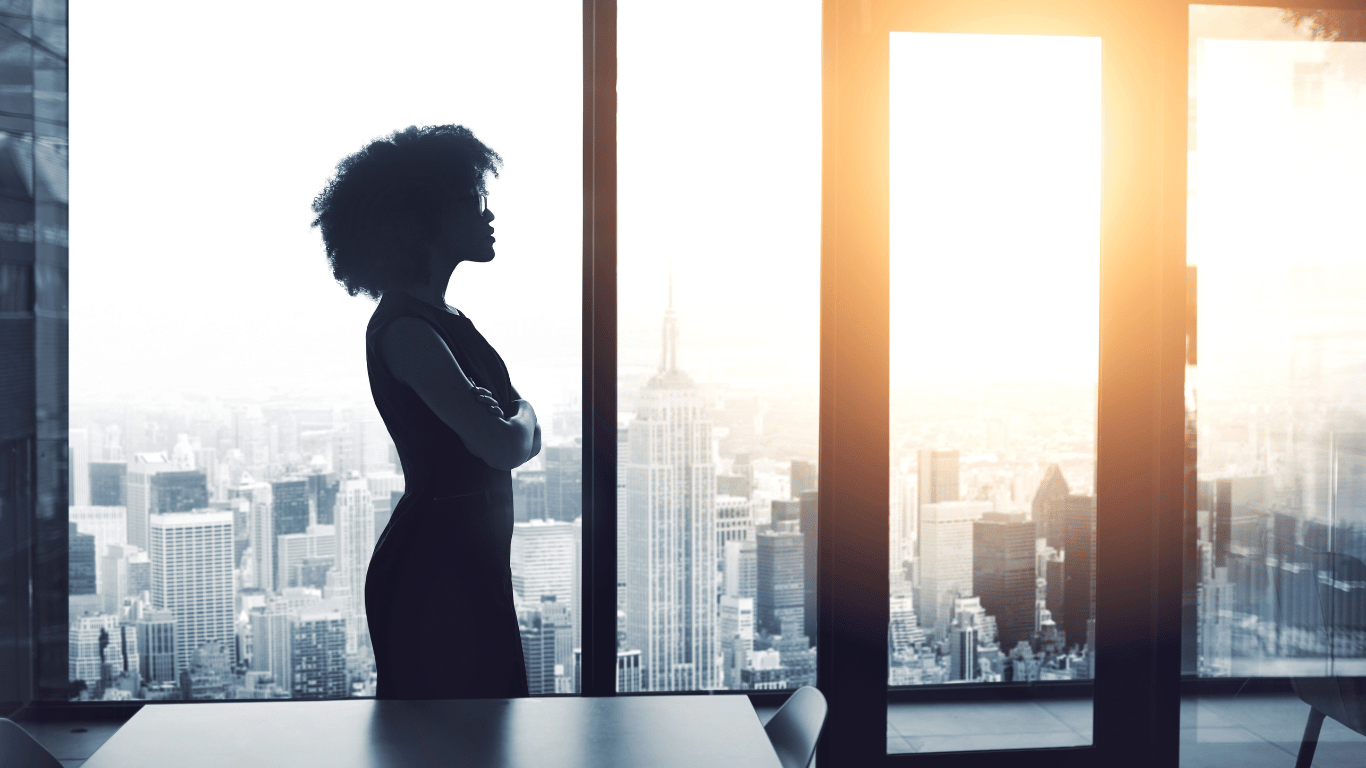 A female CEO looking thoughtfully out a window.